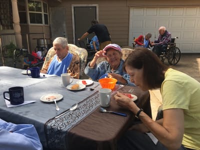 Residents enjoying a meal outdoors at a table