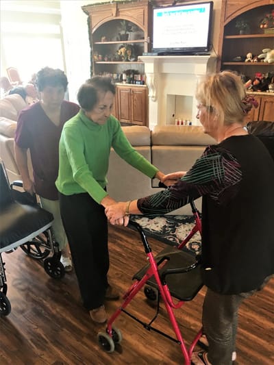 Two staff members assisting a resident with a walker