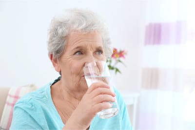 Senior woman drinking a glass of water indoors