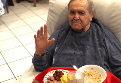 A resident enjoying a meal while waving hello