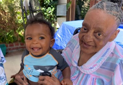 A resident smiling with a baby outdoors