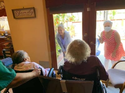 Residents interacting with staff through a glass door