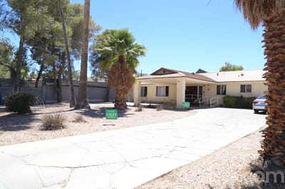 Exterior view of Dignified Care Manor with palm trees