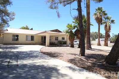 Exterior view of Dignified Care Manor surrounded by palm trees