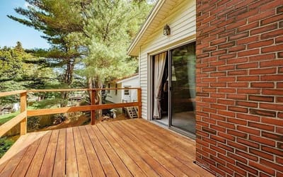 Outdoor deck area with wooden railing and trees
