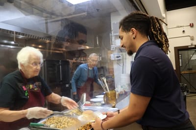 Staff serving food to a resident in the kitchen
