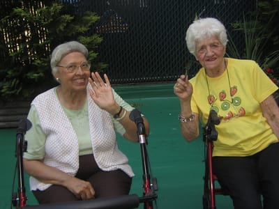 Two residents smiling and waving outdoors