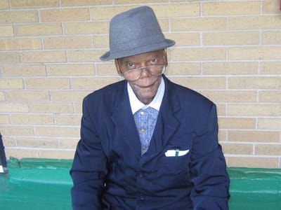 An elderly man wearing a suit and glasses