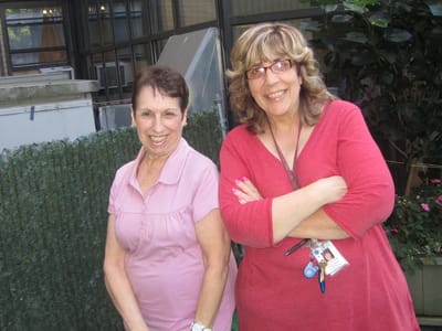 Two women smiling outdoors in a garden area