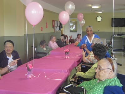 Residents engaged in an event decorated with pink balloons