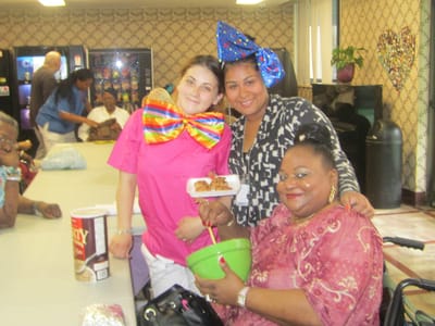 Residents and staff in a festive activity room with food