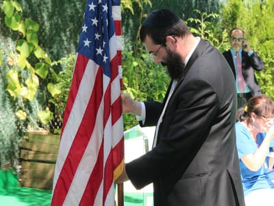 A man adjusting the American flag outdoors during a ceremony