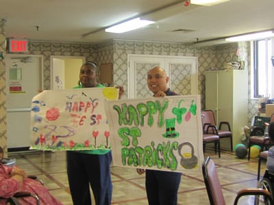 Two residents holding festive art for St. Patrick's Day
