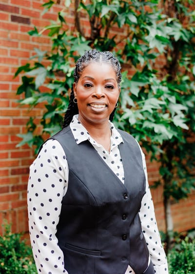 Staff member smiling in front of greenery