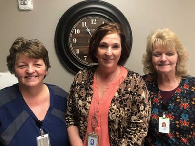 Three staff members smiling in an office environment