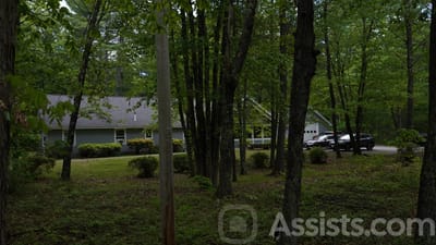 Exterior view of a senior living home surrounded by trees