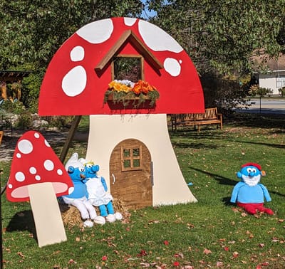 Colorful mushroom playhouse with Smurf characters in a garden.