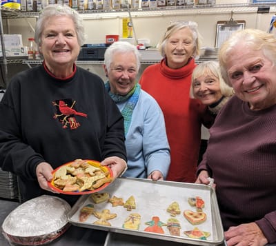 Residents enjoying cookie decorating activity in the kitchen.