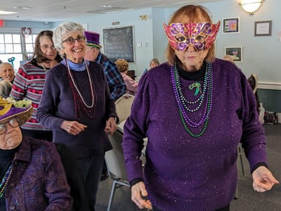 Residents celebrating with festive masks and beads.