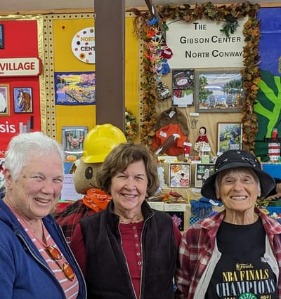 Three women smiling in a decorated common area.