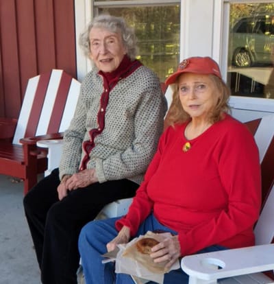 Two women enjoying snacks on a porch