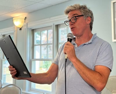 Man singing into a microphone in a common area.