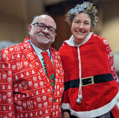 Two cheerful staff members in holiday attire.