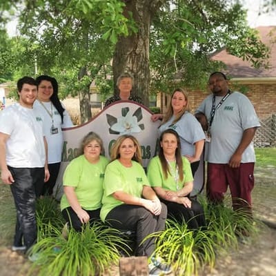 Staff members posing by the facility sign outdoors.