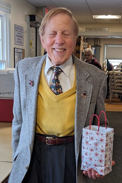 A smiling resident holding a gift in an interior space.