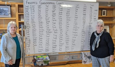 Two residents beside a large whiteboard of cookie names.
