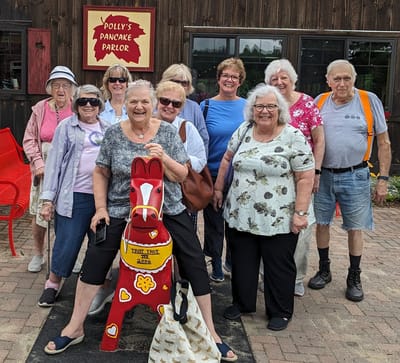 Group of residents smiling outdoors with a decorative statue.