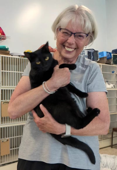 Senior woman happily holding a black cat.