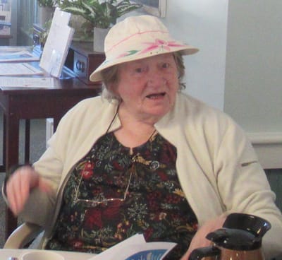 Elderly woman engaging in conversation indoors.