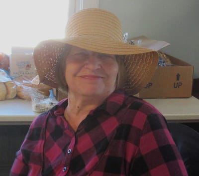 Smiling woman wearing a straw hat indoors.