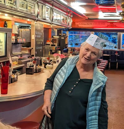 Senior woman wearing a festive waitress hat in a diner
