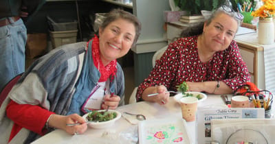 Two women enjoying salads together at a table.