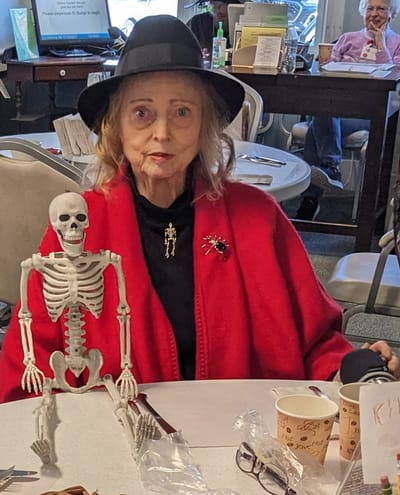 Senior resident with a skeleton prop in common area.