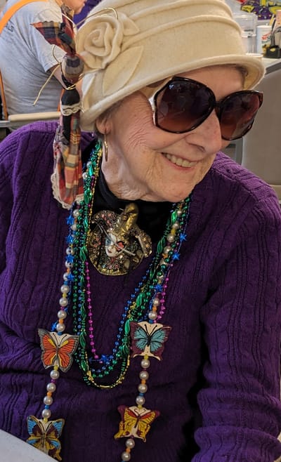 Elderly woman wearing colorful accessories and smiling.