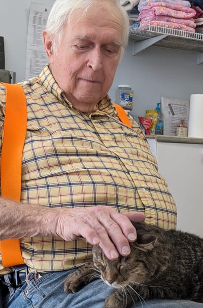 Senior man petting a cat in a facility