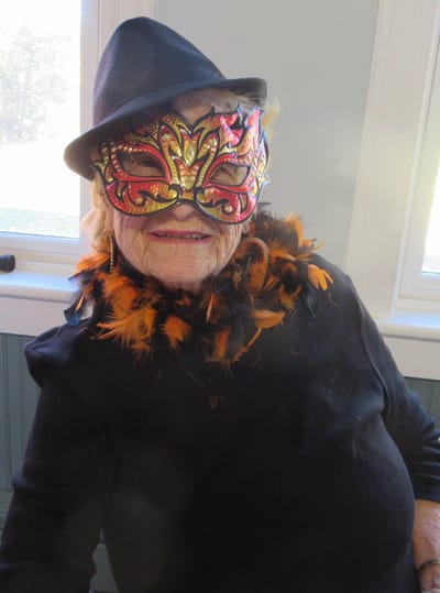Senior woman wearing a mask and festive attire.
