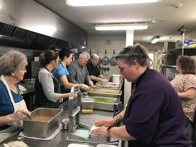 Staff and volunteers preparing food in the kitchen.