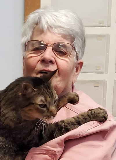 A smiling resident holding a cat in a facility setting.