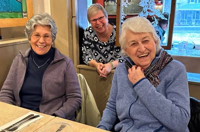 Three smiling women enjoying a gathering indoors.