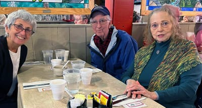 Three residents enjoying a meal together in a dining area.