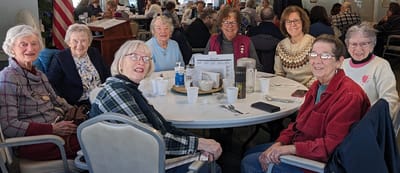 Group of residents enjoying social time at a dining table.