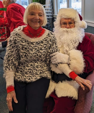 Resident smiling with Santa during a holiday celebration