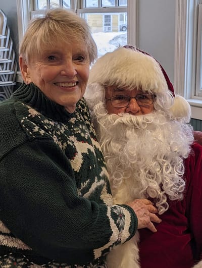 Resident smiling with Santa during holiday event.