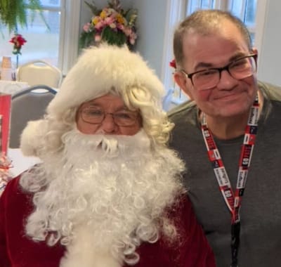 Resident and staff member celebrating with Santa Claus.