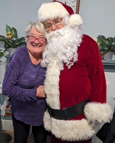 Resident joyfully posing with Santa Claus