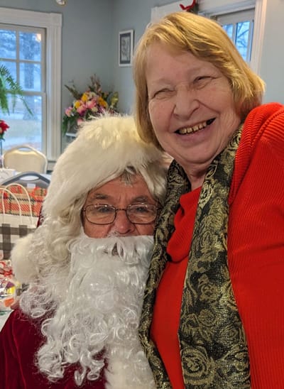 Resident joyfully posing with Santa Claus.